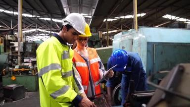 工程师和熟练技术人员在一个大型机器操作的工业设施中工作.